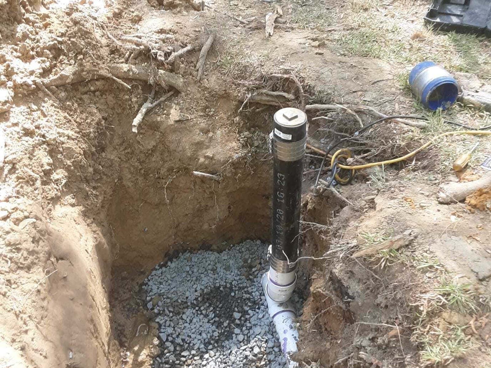 A-Team Plumbing technician running a drain machine at an outdoor cleanout on a Durham service call